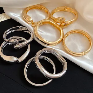 Dettaglio di bracciali a goccia incrociati lucidi in finitura oro e argento