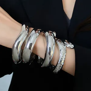 Visuale macro dettagliata di bracciali rigidi argento con trame metalliche lisce e martellate