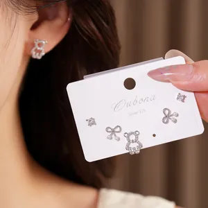 Detailed view of fashionable silver zircon bear and bow stud earrings on display card