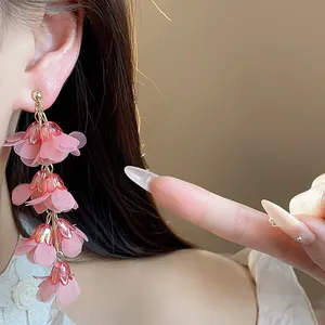 Close-up detail of elegant pink chiffon flower tassel earrings worn by a model.