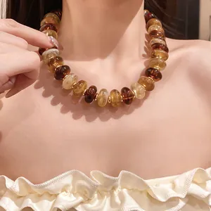 Detailed close-up of a marbled amber acrylic bead necklace worn as a stylish choker