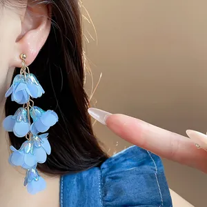 Close-up of blue chiffon flower tassel earrings worn by a model in detail.