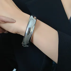 Primo piano di un bracciale rigido d'argento liscio al polso con un elegante blazer nero