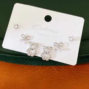 Close-up of Silver 925 earring set featuring bear, bow, and cubic zirconia designs