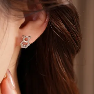 Detailed close-up of a sparkling zircon bear stud earring worn on an earlobe.