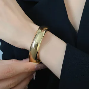 Vista dettagliata di un grosso bracciale rigido dorato lucido dal design minimalista