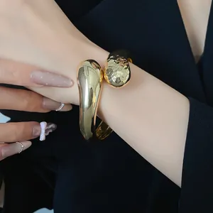Dettaglio del bracciale rigido incrociato a goccia d'oro con texture lisce e martellate
