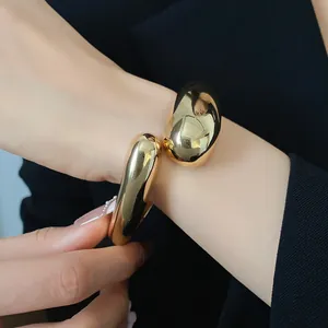 Dettaglio della finitura lucida e della forma a goccia del bracciale dorato aperto