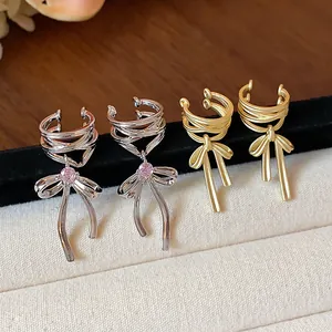 Detail view of elegant silver and matte gold bow ear cuffs accented with pink zircon stones.