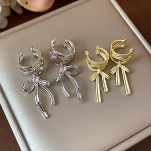 Detail view of silver and gold bow ear cuffs with pink zircon for non-pierced ears.