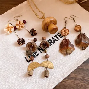 Handmade wooden mushroom necklace and botanical earrings shown on a natural canvas bag