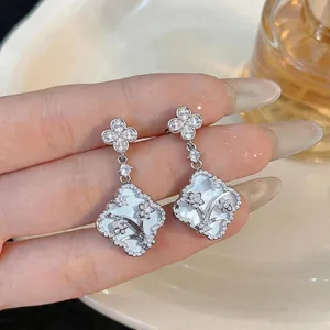 Elegant flower-shaped mother-of-pearl earrings with sparkling zircon embellishments.