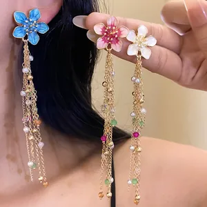 Gros plan de boucles d'oreilles fleurs en émail vintage avec perles et pompons