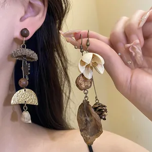 Detailed view of handmade nature-inspired long earrings with wood and dried flower accents
