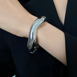 Dettaglio ravvicinato di un bracciale in metallo ondulato lucido argento al polso