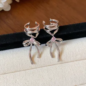 Close-up of elegant silver bow ear cuffs with sparkling pink zircon details.