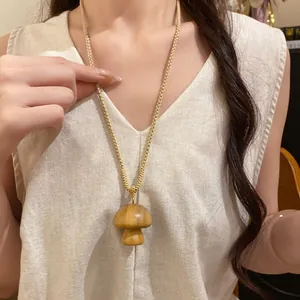 Close-up of a handmade wooden mushroom pendant on a woven cotton cord necklace.
