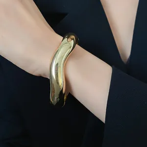 Primo piano di un bracciale a fascia irregolare dorato lucido per un look di alta moda