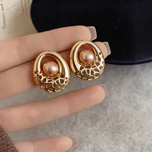 Close-up detail of elegant gold-toned hollow round stud earrings with center pearl