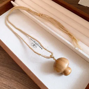 Detail view of handmade wooden mushroom pendant necklace with woven cotton cord