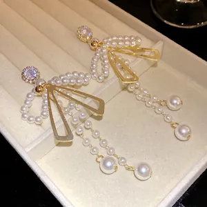 Detail view of vintage pearl bow tassel earrings with sparkling rhinestones in a tray.
