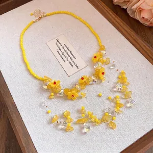 Collana di perle di fiori in resina gialla con nappe di cristallo su vassoio elegante