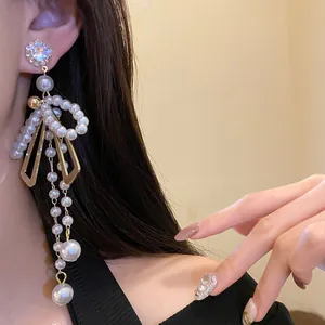 Detail view of French vintage pearl bow tassel earrings with crystal studs on a model