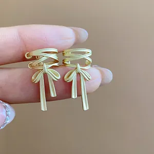 Detail view of matte gold bowknot ear cuffs showing minimalist ribbon design and texture