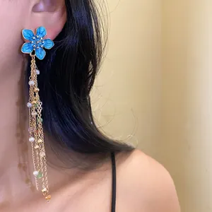 Gros plan sur des boucles d'oreilles pendantes fleurs en émail bleu vintage et perles