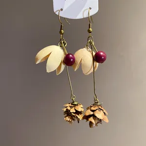 Macro view of handmade earrings with natural pinecone detail and vintage cream petals
