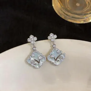 Macro view of mother of pearl flower earrings with intricate zircon floral overlays.