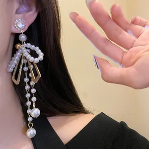 Elegant crystal stud earrings with pearl bow and long tassel detail for women.