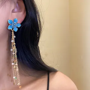 Vue détaillée de boucles d'oreilles fleur bleue avec de délicates franges en or fin