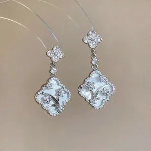 Close-up view of elegant silver flower earrings featuring mother-of-pearl and zircons