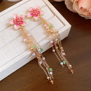 Gros plan de boucles d'oreilles fleur émaillée vintage avec pompons et perles colorées