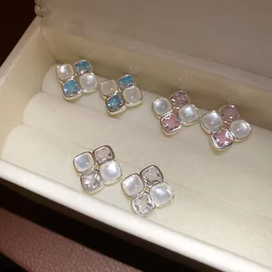 Close-up view of square zircon and resin stud earrings in three colors in a jewelry box