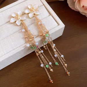 Gros plan de boucles d'oreilles fleur blanche avec pompons dorés et perles