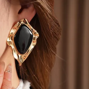 Large geometric irregular stud earrings with black enamel center and gold-tone metal frame
