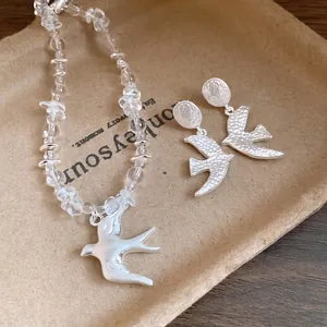 Crystal beaded necklace and swallow earrings jewelry set on kraft paper background