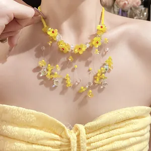 Elegante collana di fiori in resina gialla con frange di cristallo indossata da modella.