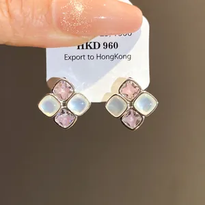 Close-up of elegant rhombic stud earrings with pink and white stones