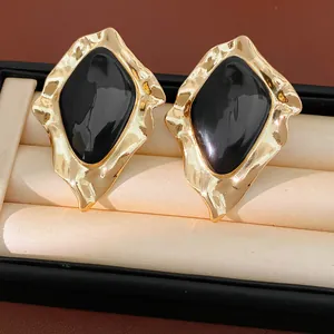 Detailed macro shot of vintage gold-tone irregular geometric earrings with black enamel