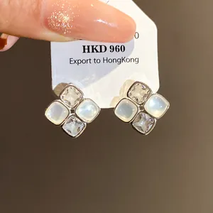 Close-up of zircon and resin square stud earrings on a white display card.