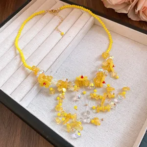 Dettaglio macro di una collana di perline con fiori e nappe in cristallo giallo