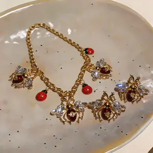 Detailed macro shot of vintage jewelry set featuring enamel ladybug and crystal bee charms