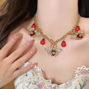 Detailed view of vintage-inspired gold ladybug and insect pendant necklace on model