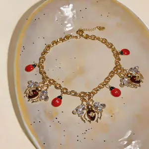 Close-up of vintage gold necklace with enamel ladybug and rhinestone bee charms