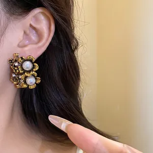Elegant vintage gold flower stud earrings with pearls and rhinestones worn on ear