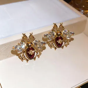 Close-up of luxury vintage gold-tone bee earrings with clear crystals and red stones