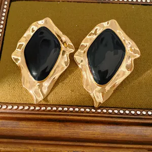 Macro detail of vintage irregular gold stud earrings with black enamel center inlay.